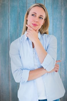 Pretty blonde thinking with hand on chin against wooden planks