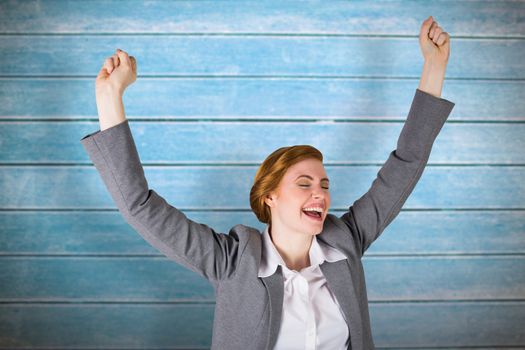 Excited redhead businesswoman cheering against wooden planks