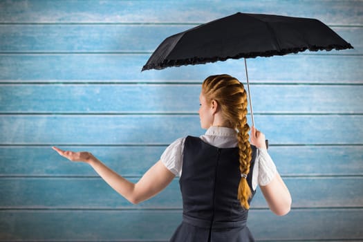 Pretty redhead businesswoman holding umbrella against wooden planks