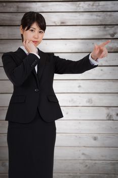 Thoughtful businesswoman pointing against wooden planks