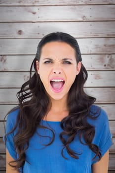 Angry brunette shouting at camera against wooden planks