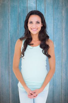 Pretty brunette smiling at camera against wooden planks