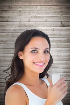 Pretty brunette drinking glass of water against wooden planks background