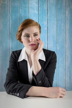 Thinking redhead businesswoman against wooden planks