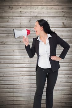 Pretty businesswoman shouting with megaphone against wooden planks background