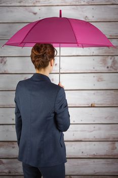 Businesswoman with umbrella against wooden planks