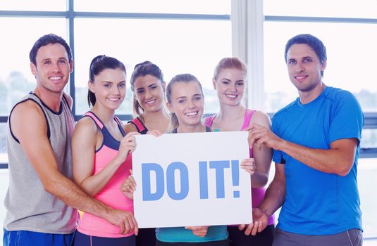 The word do it! against portrait of a group of fitness class holding blank paper