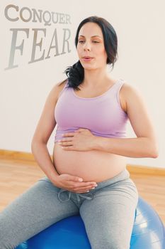 Pregnant brunette sitting on exercise ball breathing against conquer fear