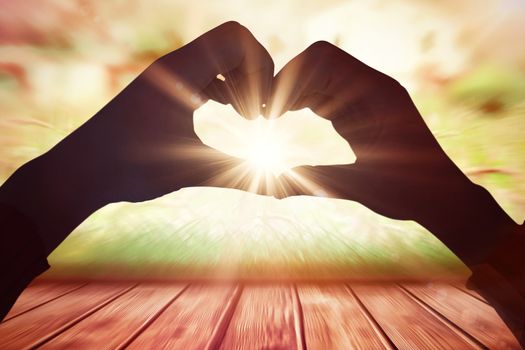 Woman making heart shape with hands against wooden planks against farm scene