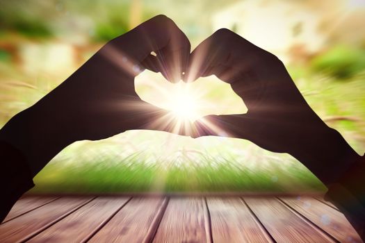 Woman making heart shape with hands against wooden planks against farm scene