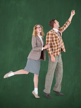 Happy geeky hipster couple holding their hands  against green chalkboard