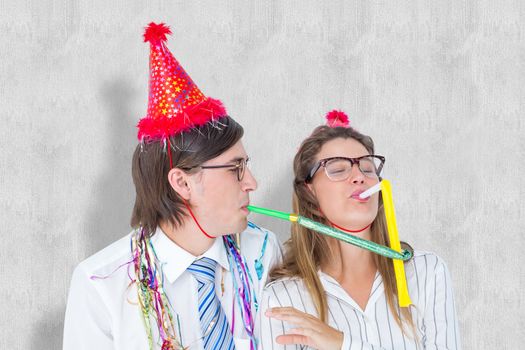 Geeky hipster wearing a party hat with blowing party horn against white background