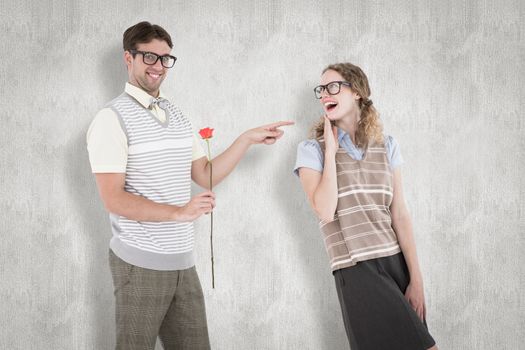 Geeky hipster holding rose and pointing his girlfriend  against white background