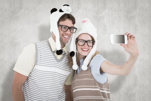 Geeky hipster couple taking selfie with smartphone against white background