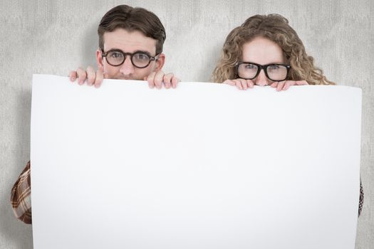Geeky hipster couple holding poster against white background
