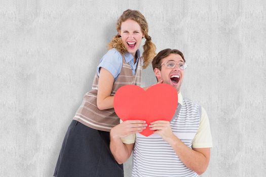 Excited geeky hipster couple with heart card  against white background