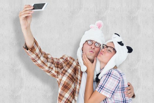 Geeky hipster couple taking selfie with smart phone  against white background