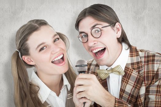 Happy geeky hipsters singing with microphone against white background