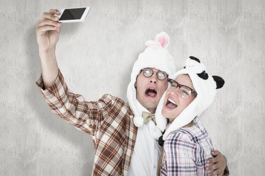 Geeky hipster couple taking selfie with smart phone  against white background