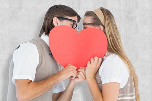 Geeky hipsters kissing behind heart card  against white background