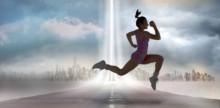 Fit brunette running and jumping against city on the horizon with light beam