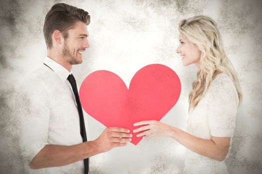 Attractive young couple holding red heart against grey background