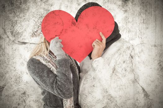 Couple in winter fashion posing with heart shape against grey background