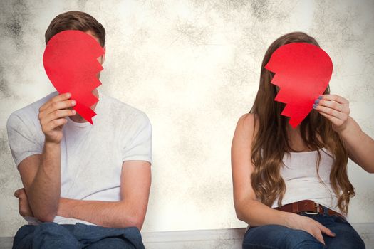 Couple holding broken heart against grey background