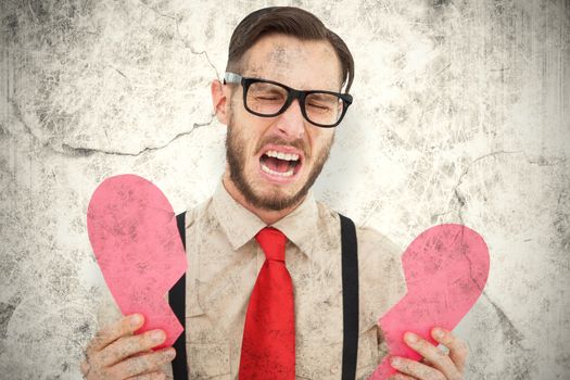 Geeky hipster crying and holding broken heart card against grey background