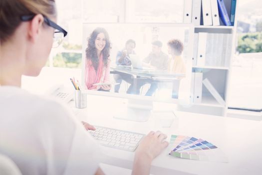 Composite image of smiling designer using tablet in office