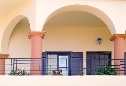 Detail of the facade of an old house on the coast of the island of Crete with a long balcony, fenced wrought metal fence.