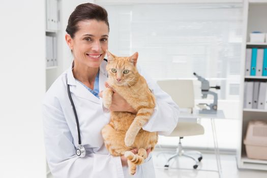 Smiling veterinarian with a cute cat in her arms in medical office