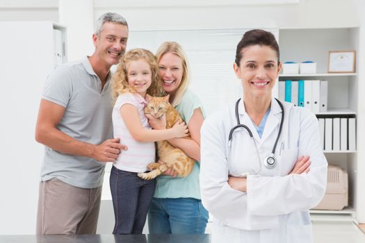Veterinarian and cat owners smiling at camera in medical office 