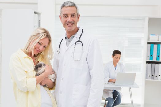 Veterinarian and cat owner smiling at camera in medical office 