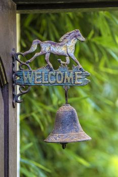 Metal sign welcome on the door with horse sculpture.