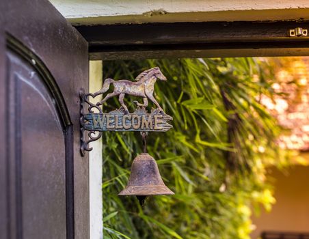 Metal sign welcome on the door with horse sculpture.