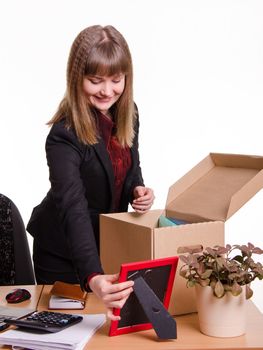 The girl accepted a job at the office and arranges personal belongings at the new workplace