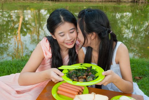 Asian Thai sister picnic together beside swamp.