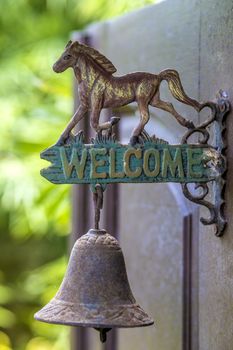 Metal sign welcome on the door with horse sculpture.