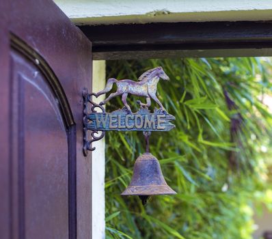 Metal sign welcome on the door with horse sculpture.