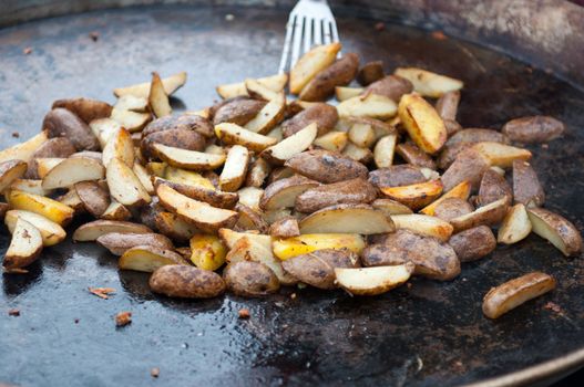 Delicious fried potatoes on the fire in a large pan.