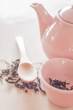 Dry tea and wooden spoon with ceramic jar, stock photo