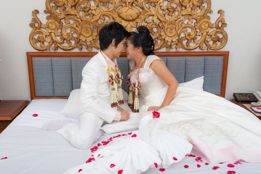 Asian Thai Bride and Groom on a Bed in Wedding Day.