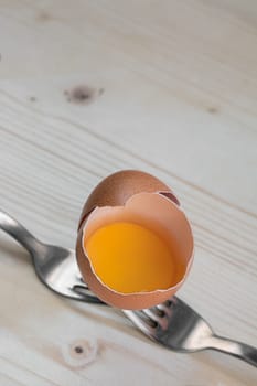 open egg resting on two steel forks