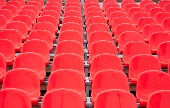 Empty bright red plastic seats in a stadium.