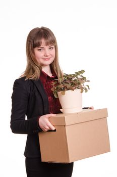 Smiling girl adopted at work in the office holding a box with things and flower room