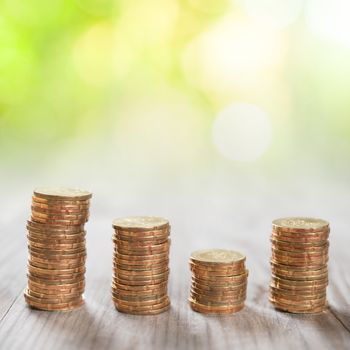 Coins stack in row on wooden background, financial concept. Focus on foreground with blur nature green background.