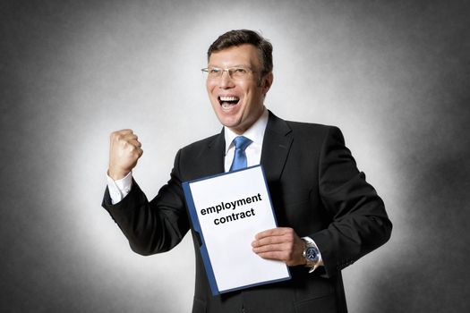 Image of happy business man with fist in dark suit and with employment contract
