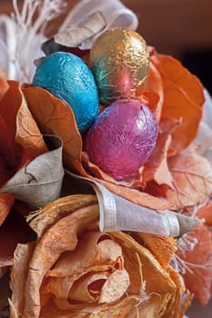 three colored chocolate eggs in a basket of flowers