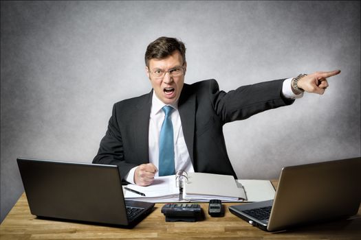 image of angry business man in suit who is screaming and pointing with finger in his office